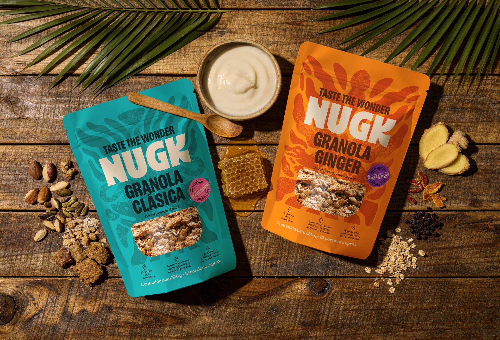 Two stand-up pouches of NUGK Granola are arranged on a rustic wooden surface with food props. The left pouch is teal and labeled Granola Clásica, and the right pouch is orange and labeled Granola Ginger. Shop